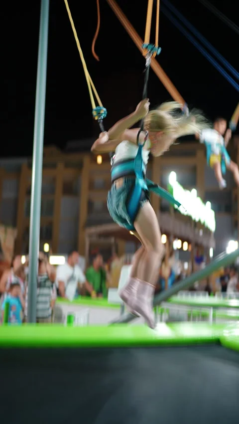 Girl jumping in harness at fair Stock Footage 313485706