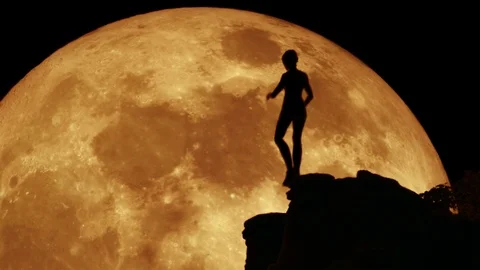 Girl Jumping from Ledge to Ledge in front of Large Yellow Moon Stock Footage 100525554