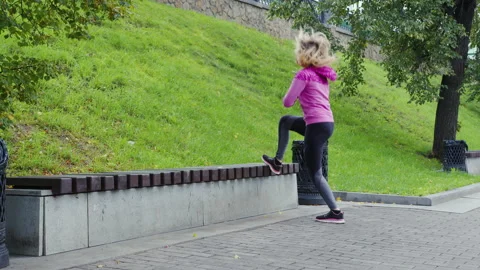 Girl jumping on a park bench Stock Footage 194836469