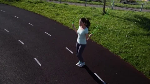 A girl is jumping rope on a treadmill of the stadium Stock Footage