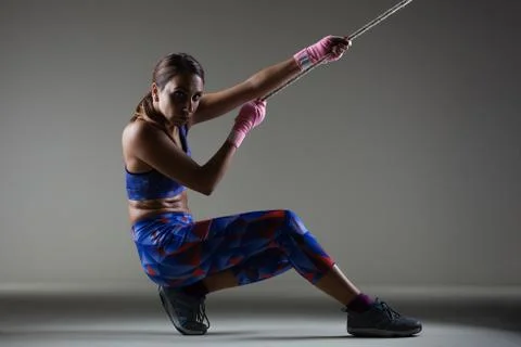 Girl kickboxer pulling a chain with pink hand wraps. Stock Photos