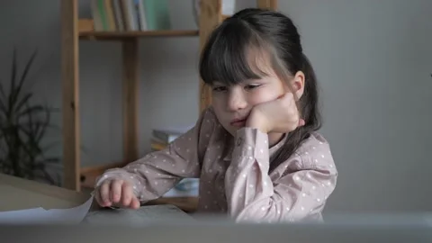 Girl kid is bored while studying online. Child making boring face while watching Stock Footage