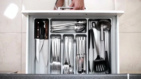 Girl in the kitchen pulls out a drawer with a set of chrome cutlery. Stock Footage 145434582