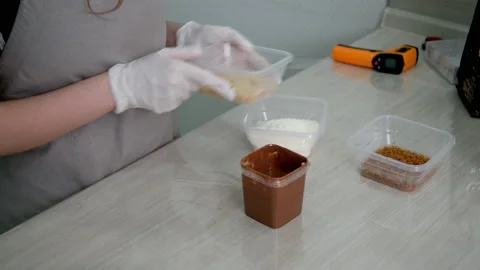 The girl in the kitchen puts on the table coconut shavings and waffle crumbs. Stock Footage 155928732