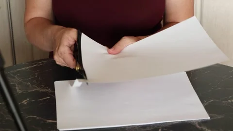 A girl at the kitchen table cuts white paper with scissors Stock Footage 316790449