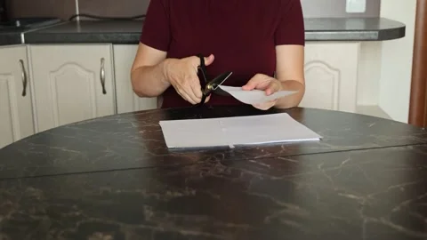 A girl at the kitchen table cuts white paper with scissors Stock Footage 316791257