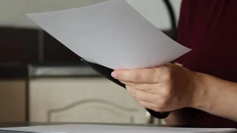 A girl at the kitchen table cuts white paper with scissors Stock Footage 316791891