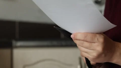 A girl at the kitchen table cuts white paper with scissors Stock Footage 316792022