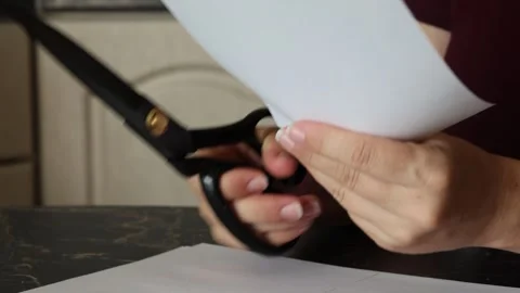 A girl at the kitchen table cuts white paper with scissors Stock Footage 316792152