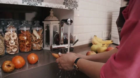 A girl in the kitchen washes fruit under the tap Stock Footage 200946245