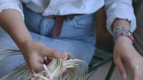 A girl knits a braid from dry grass. Close-up of hands doing needlework. Manual Stock Footage 256079705