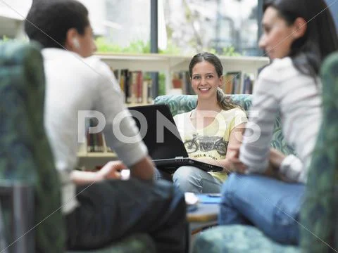 Girl With Laptop Looking At Friends In Library