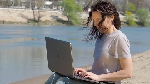 Girl with a laptop by the water. Stock Footage