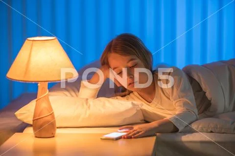 The girl lay on the bed and phone. Evening night time Stock Photos