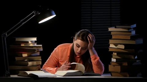 Girl leafing through a book yawns and falls asleep. Black background Stock Footage