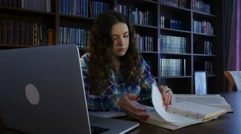 Girl leafing through a notebook in the library. 4K Stock Footage 63503026