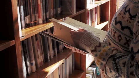 A girl leafing through the pages of a book in the library. Close-up video Stock Footage 260738136