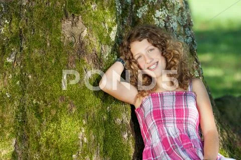 Girl leaning on tree trunk Stock Photos