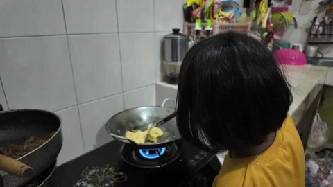 A girl is learning to cook scrambled eggs using a frying pan Vídeos de archivo 291672785