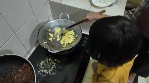 A girl is learning to cook scrambled eggs using a frying pan Vídeos de archivo 291672852