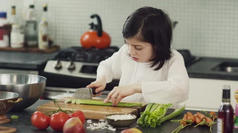 Girl learning to cut vegetable in kitchen Stock Footage 63860621