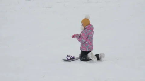 Girl learning to ride a mountain slope on a snowboard Stock Footage 59140213