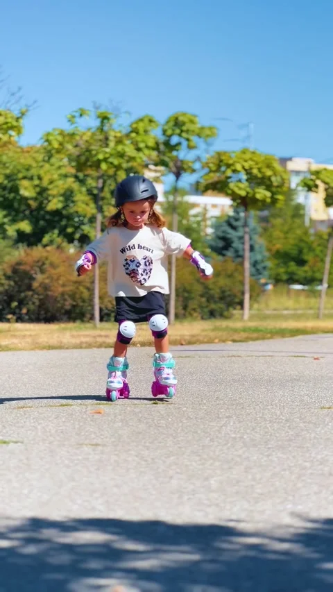 Girl learning to roller skate in protective gear Stock Footage 344605639