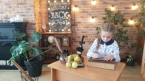 A girl is learning to write with chalk on a board, sitting at her desk Stock Footage 169048022