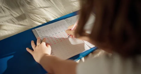 The girl learns to write numbers in a notebook with a pen. Stock Footage 243211245