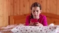 Girl lies on the bed and talks on smartphone HD Footage