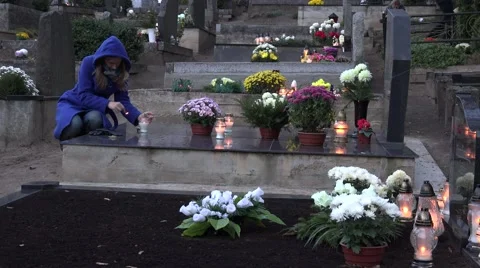 Girl light candle lantern in memory of husband father in cemetery. 4K Stock Footage 64330926