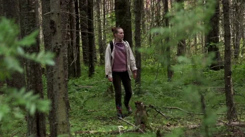 A girl in a light jacket wanders alone through the green forest Stock Footage 201602822