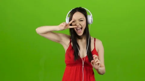 Girl listens to cheerful music through headphones and dances. Green screen Stock Footage