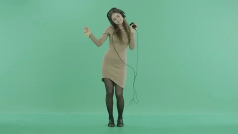 A girl listens to music with headphones and dances Stock Footage