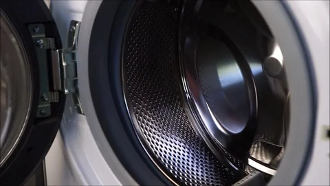 A girl loads colored things into a white washing machine Stock Footage 130109770