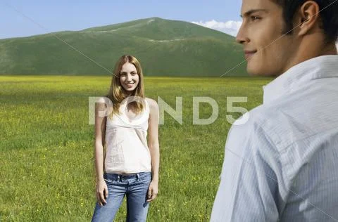 Girl Looking At Boyfriend While Standing In Field Stock Photos