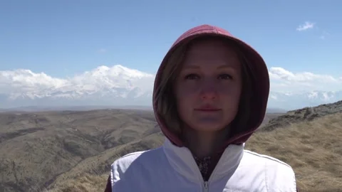 Girl looking at the camera on a background of a sleeping volcano Stock Footage 133228446