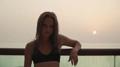 Girl looking at the camera on the background of the sunset. Видео 167734858