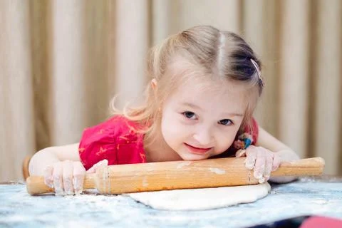 Girl looking at camera while rolling a dough Фото