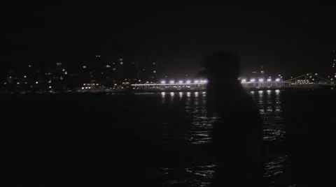 Girl looking at the city lights on the water Stock Footage