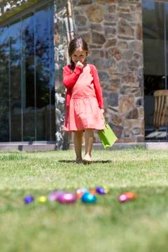 Girl looking at Easter eggs in a lawn Stock Photos