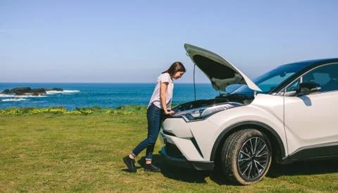 Girl looking engine of broken down car Stock Photos