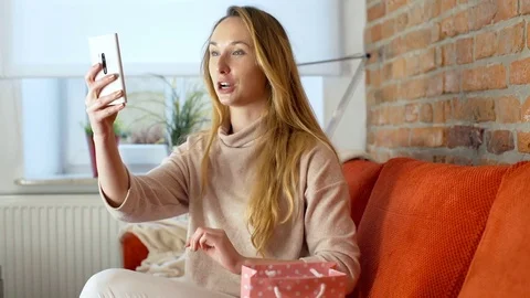 Girl looking happy while talking on smartphone and showing her shopping 스톡 동영상 70377812