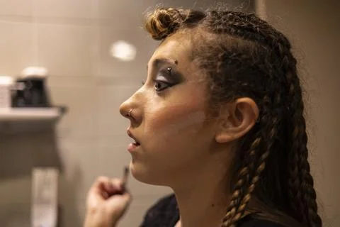Girl looking at herself in the mirror while putting on her make-up Foto stock