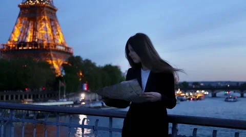 Girl looking map in Paris at the Eiffel tower in the evening Stock Footage 64071285