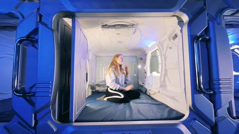A girl is looking into a mirror of a capsule hotel room Stock Footage