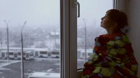 Girl looking out the window at the snowfall Stock Footage 74780700