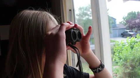 Girl looking out the window through her binoculars Vídeos de archivo 53767222
