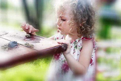 Girl looking at a snail on a table Stock Photos