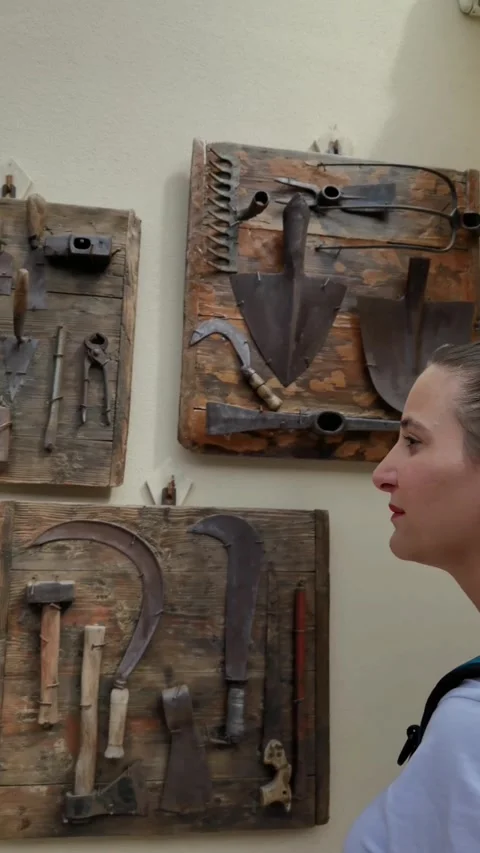 A girl looking at some old work tools hanging on a wall Stock Footage 247073633